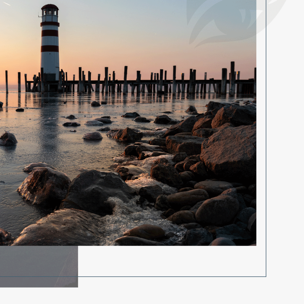 Der Leuchtturm in Podersdorf bei Sonnenuntergang mit zugefrorenem See.